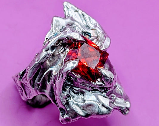 Close-up of molten silver claws holding deep red gem – unique handcrafted jewellery
