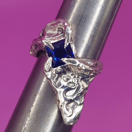 Close-up video of handmade silver ring with sapphire on mandrel – flowing silver texture and deep blue gem