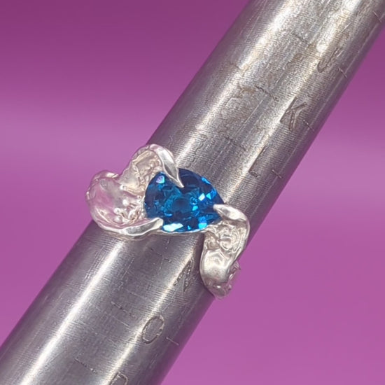 Close-up video of handmade silver ring on mandrel – pear-cut blue nano gem and sculpted silver texture