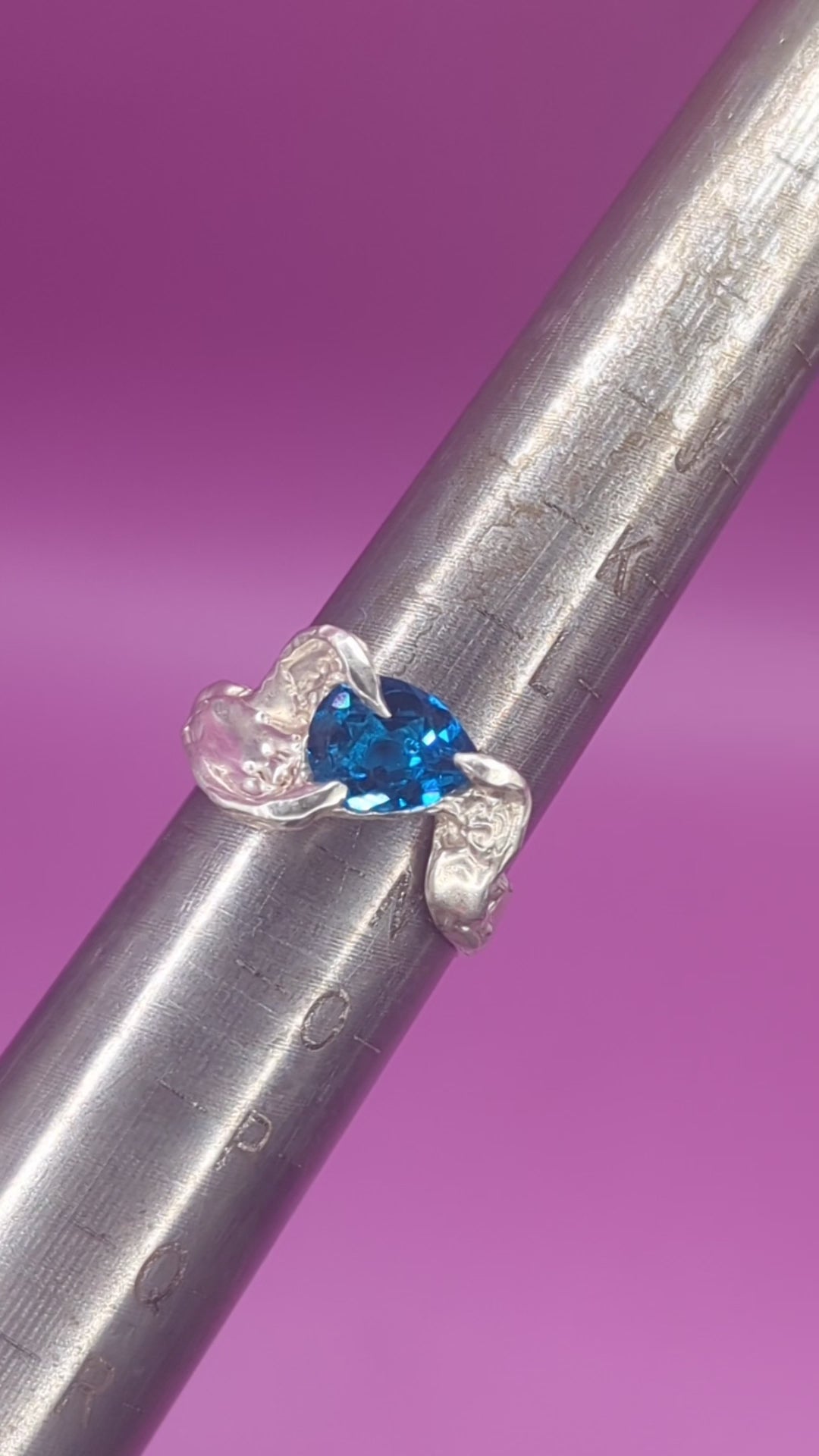 Close-up video of handmade silver ring on mandrel – pear-cut blue nano gem and sculpted silver texture