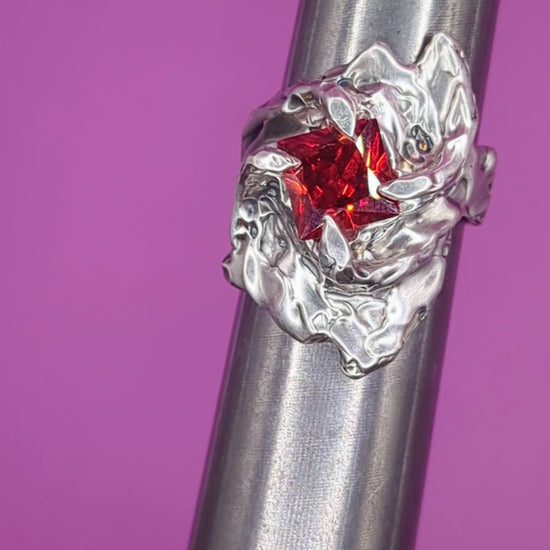 Close-up video of Fusion ring on mandrel – molten silver band with red square garnet gem

