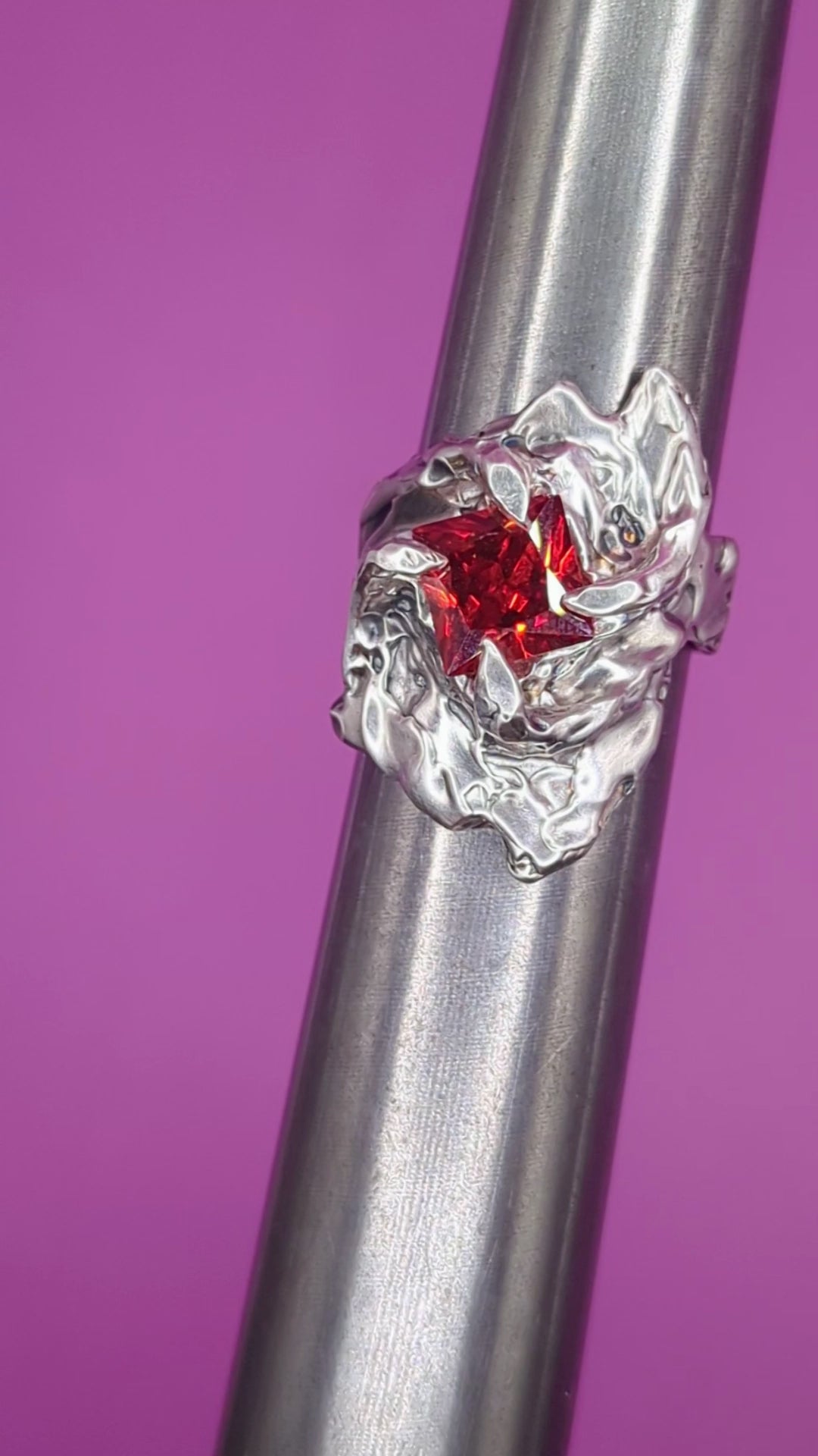Close-up video of Fusion ring on mandrel – molten silver band with red square garnet gem

