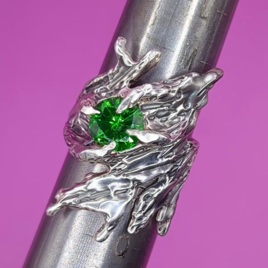 Close-up video of handmade silver ring with green CZ on mandrel – textured band and bold gem
